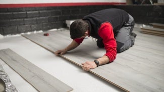 Young man placing a laminate floor - stock photo