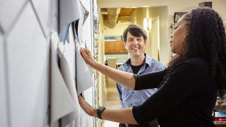 Two architects sharing ideas as they pin them on the board.