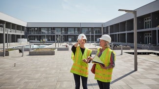 Architects in PPE gear evaluating a project at a construction site.