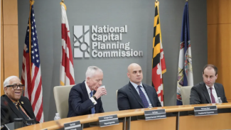 Four Commissioners sit at their desks in front of the National Capital Planning Commission Logo