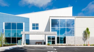 exterior of white and blue PEMB amidst landscaping