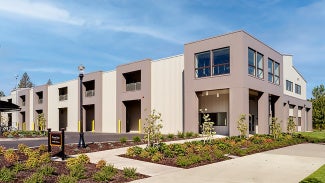 exterior of gray and white pre-engineered metal building with landscaping