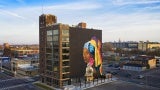 Aerial view of a multi story building with a mural painted on the rear facade. 