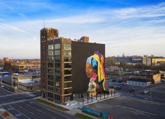 Aerial view of a multi story building with a mural painted on the rear facade. 