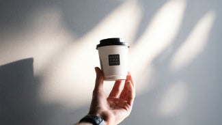 Barista holding a Grace Street to-go coffee cup