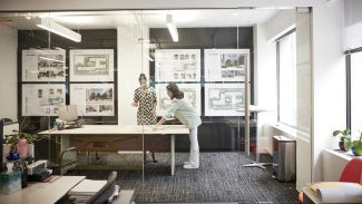 Two architects having a conversation over architectural drawings in their office