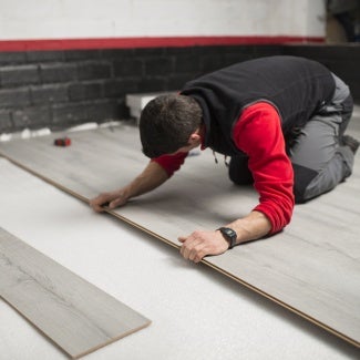 Young man placing a laminate floor - stock photo