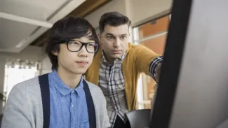 Student and teacher looking at computer