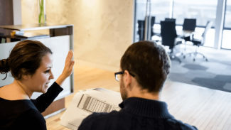 Two people discussing floor plans in an office