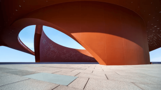 Architectural concept rendering of an reddish orange metal curved building