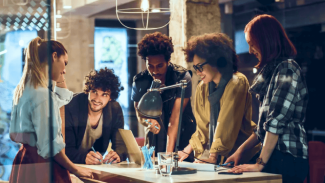 Group of young architects standing around a table having a discussion