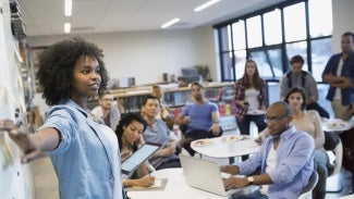 educator speaks a whiteboard to a room full of people