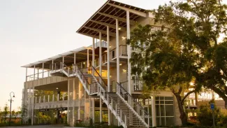 Modern 3 story building at sunset, with stairs on the exterior leading up to the second floor