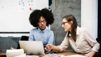 two woman looking at a laptop