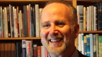 Headshot of man with beard in front of bookcase