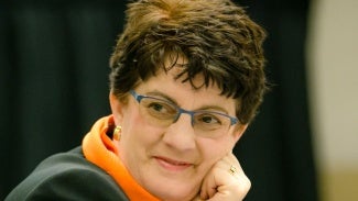 headshot of woman with short hair and glasses resting her chin on her hand