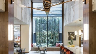 Interior view reflecting a counter/stool area on the right, another common area on the left and in the middle an overarching forest view through window quadrants.