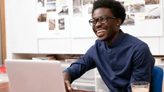 young associate smiling at a desk with laptop