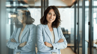 woman in suit standing and smiling in office hallway