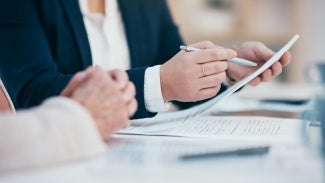 Hands closeup on contact, legal settlement or financial report while reading and making notes. Lawyer team doing work and analyzing documents. Lawyers looking through client finance data together