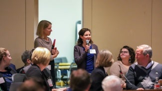 Woman speaks on microphone to a committee of peers