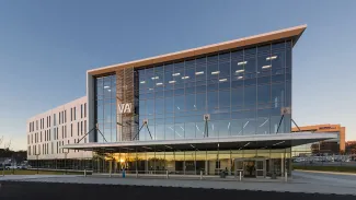 THE BUILDING'S GLASS CORNER IS FRAMED WITH CRISP WHITE LINES TO SIGNIFY ENTRY TO VISITING VETERANS. THE ARCHITECTURAL GESTURE IS AS IF THE BUILDING IS STANDING AT ATTENTION AND SALUTING.