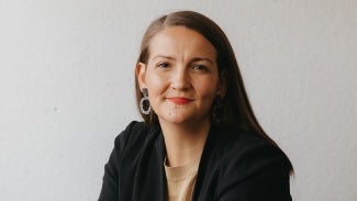 Headshot of a woman with long dark hair in a dark jacket