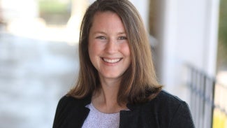 Headshot of a woman with long brown hair in a dark jacket