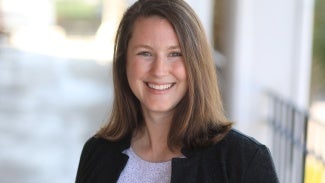 Headshot of a woman with long brown hair in a dark jacket 