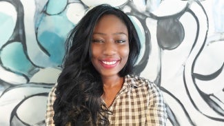 Headshot of a woman with long dark hair, wearing a checkered blouse.