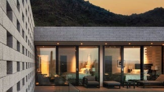 Home with warm light coming from the windows beneath a sunset