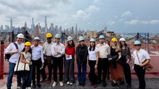 group of architecture students in hard hats in front of new york city skyline