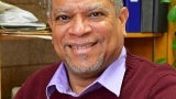 Headshot of a man wearing a collared shirt and sweater