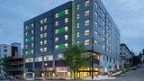 Apartment building at dusk; facade is blue with green detailing