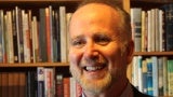 Headshot of man with beard in front of bookcase