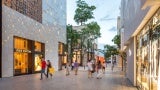 Pedestrians walk past a Louis Vitton store in a shopping district.