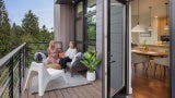 Residents sit together on outdoor patio, open door leads to kitchen area.