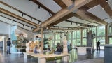 The main public exhibit space opens up with views to the north woods and south prairie, connecting interpretive content with the surrounding landscape.