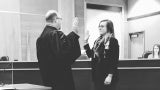 Black and white image of a woman being sworn in by a judge.