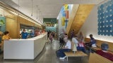 Interior of a community building with a large white front desk and colorful wayfinding. 