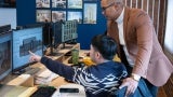 A man showing another man rendering of a house on his computer.