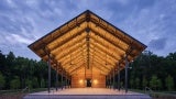 Exterior view of a wooden pavilion at night. 