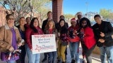 A group of people hold an announcement sign and pom-poms.