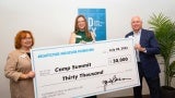 A man and two women hold and giant novelty check