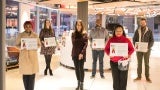 Six individuals stand in a lobby area holding award certificates.