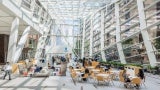Interior view of a glass atrium with tables and chairs. 