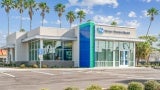 External view of a one story bank in a parking lot with palm trees in the background.