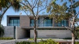 Exterior view of a gray building at day. There are trees in the foreground. 