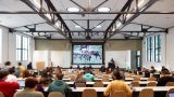 New lecture hall highlights existing truss structure and provides connections to the outdoors with generous glazing and tubular skylights