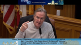 man in gray collared shirt speaking at public works commission hearing